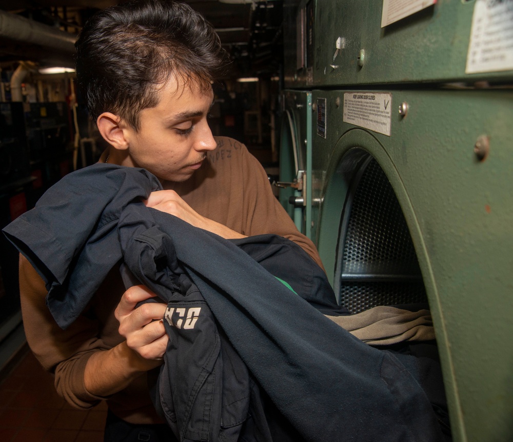 Worker removing laundry from an industrial dryer